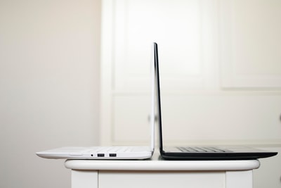 黑白笔记本电脑背靠背放在桌子上